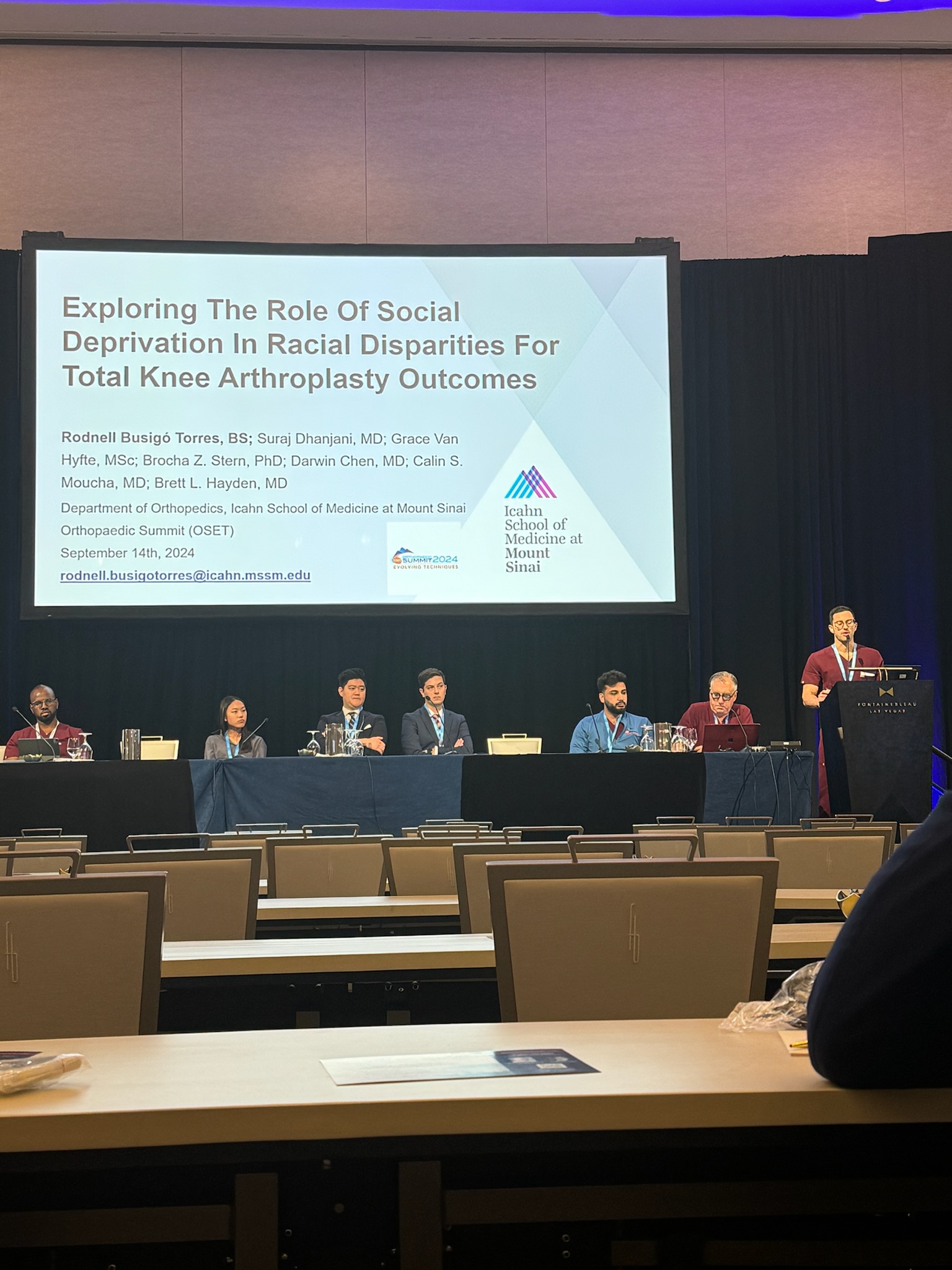 Image of Rodnell Busigó Torres (Class of 2025) giving a podium presentation on the role of social deprivation and joint replacement outcomes at the Orthopaedic Summit.
